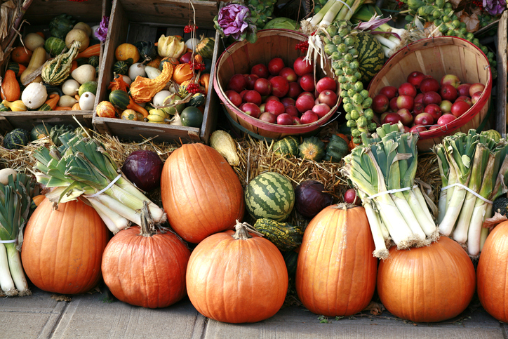 armers market display of pumpkins, red apples, leeks, Brussels sprouts, and colorful gourds for healthy plant-based fall meals